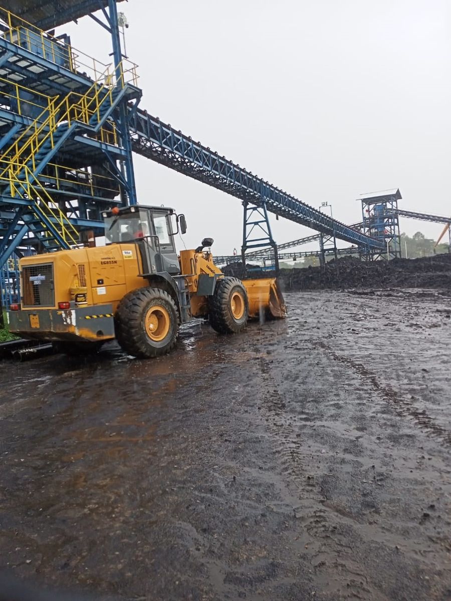 Wheel loader LiuGong bekerja di bawah conveyor saat hujan